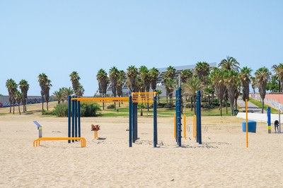 Persones banyant-se a la platja amb les tres xemeneies al fons