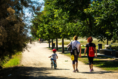 Tres persones caminen per un dels camins del parc