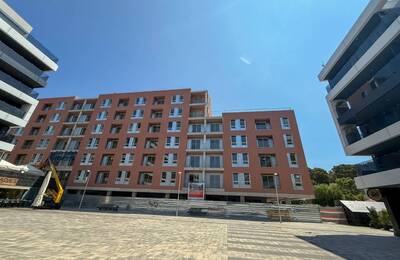 L’edifici visitat, que té una façana de diversos pisos de color marró vermellós, en procés de finalització d’obra. Està envoltat per altres edificis moderns, un a cada costat, i part de la zona és tancada. El dia és assolellat i el cel està clar.