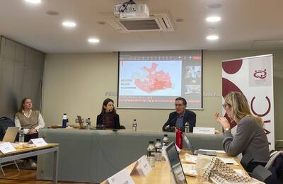 Sala de conferències amb diverses persones debatent al voltant de la taula