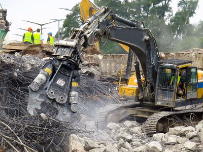 Un màquina enderroca un edifici i aixeca força pols