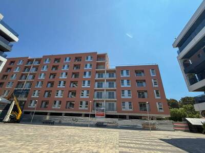 L’edifici visitat que té una façana de diversos pisos de color marró vermellós en procés de finalització d’obra. Està envoltat per altres edificis moderns, un a cada costat, i part de la zona és tancada. El dia és assolellat i el cel està clar.
