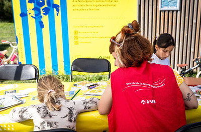 Una monitora i infants fent una activitat a la Jugatecambiental