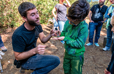 Un educador ensenyant un ocell a un infant en una activitat d'observació