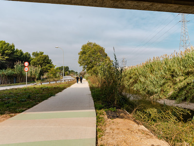 dos persones pel camí de vianants entre una carretera i el riu