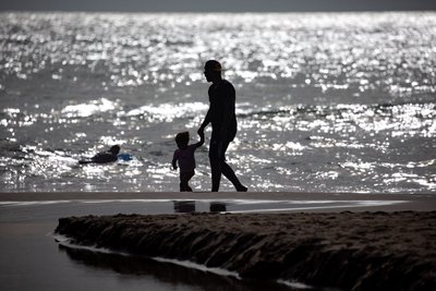 Una persona i un nen passejant per la platja al capvespre
