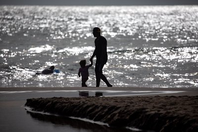 Una persona i un nen passejant per la platja al capvespre