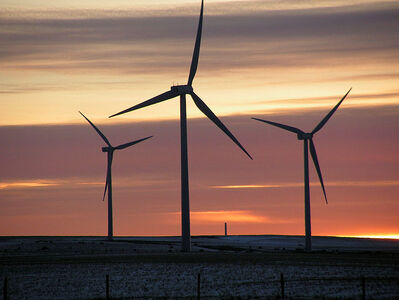 Tres aerogeneradors situats a una esplanada amb la posta del sol de fons.