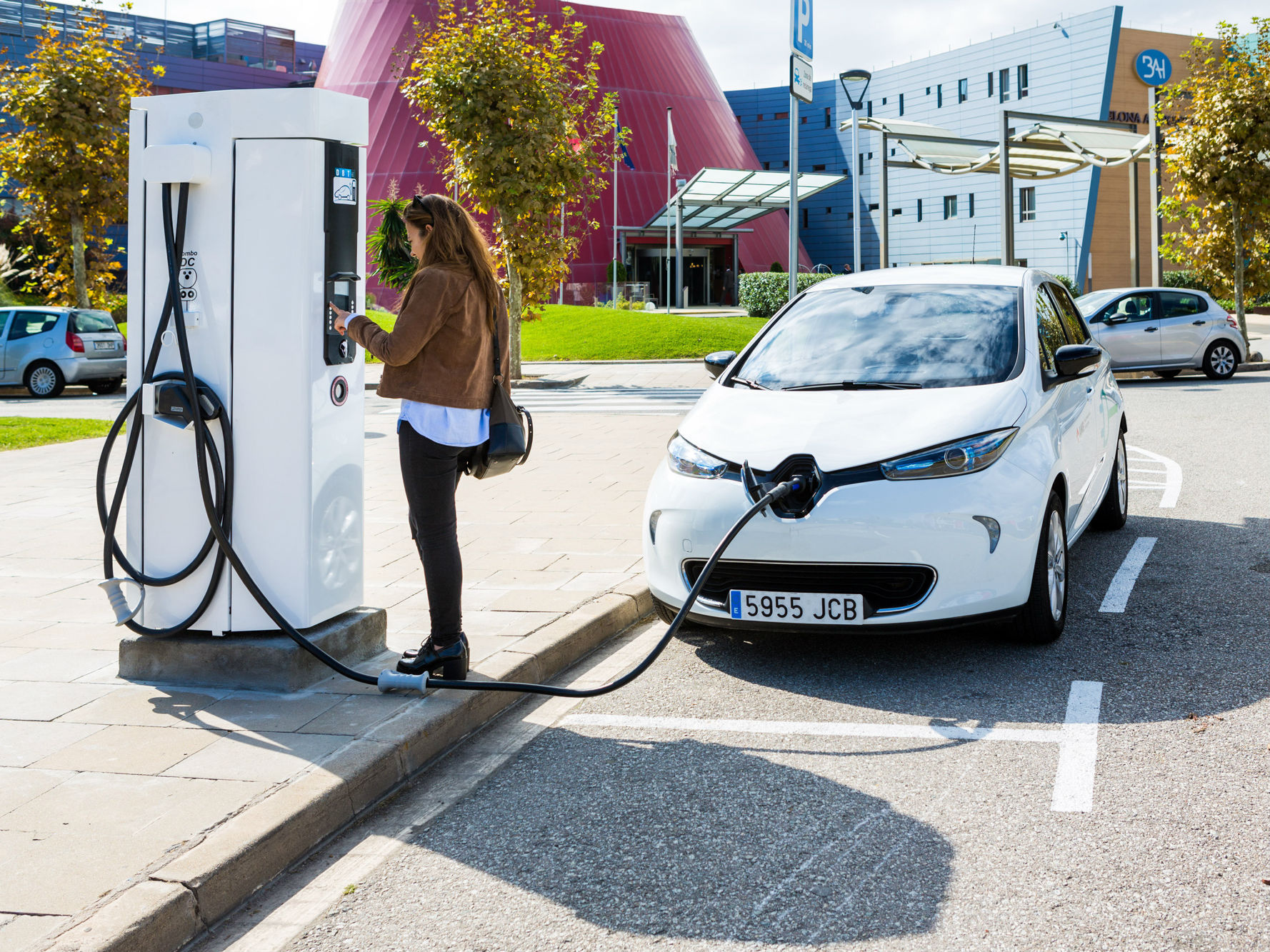 Una mujer carga su vehículo eléctrico en una electrolinera