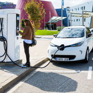 Una dona carrega el seu vehicle elèctric en una electrolinera