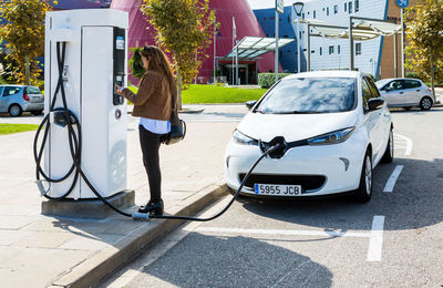 Una dona carrega el seu vehicle elèctric en una electrolinera