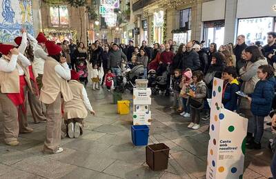 Gent al carrer escoltant nadales de la campanya