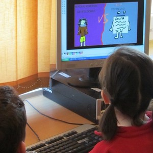 Una nena i un nen consultant alguna cosa en un ordinador