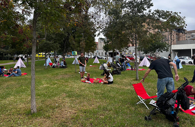 Famílies estirades a la gespa del parc en una de les activitats de la jornada festiva