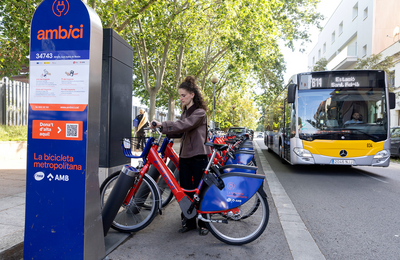 Una noia agafant una bici en una parada de l'AMBici