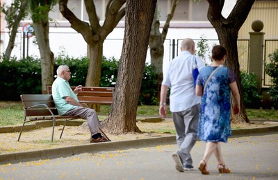 Persona gran asseguda a un banc d'un parc